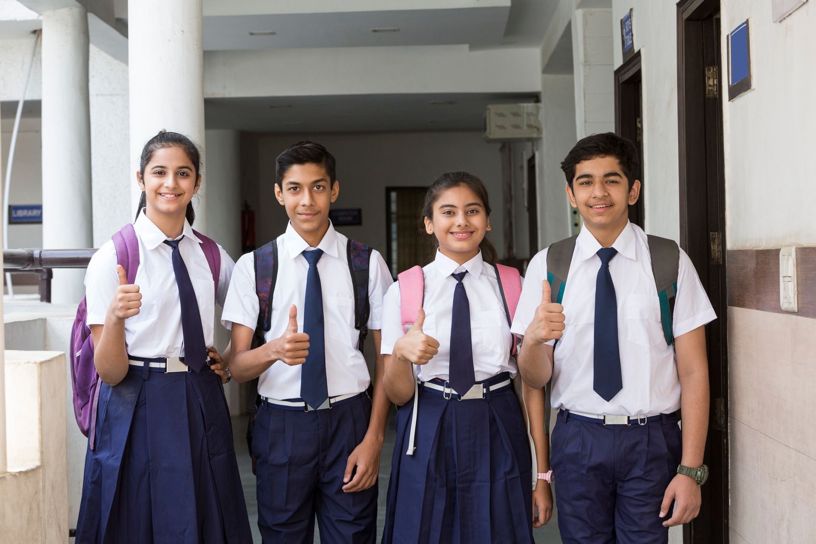 Four senior students in uniform walking down a school corridor